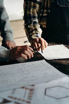 Services Close-up of hands working on blueprints in a workshop environment.