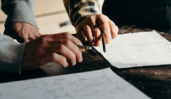 Services Close-up of hands working on blueprints in a workshop environment.