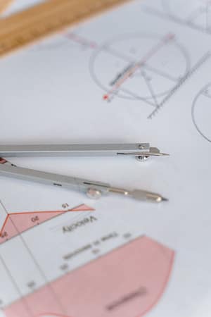 Services A close-up of a compass on geometric drawing paper, ideal for education and mathematics concepts.
