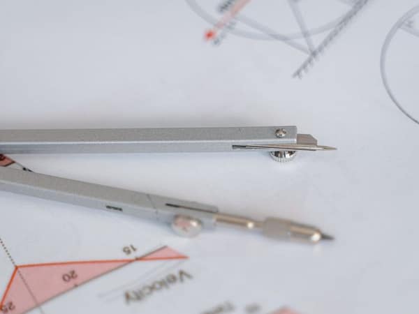 Services A close-up of a compass on geometric drawing paper, ideal for education and mathematics concepts.